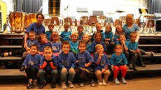 Group picture of a first-grade class sitting on steps leading to the stage in an auditorium