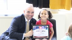 Senator Akshar smiling with Mylee Siedlecki who is sitting, holding her certificate