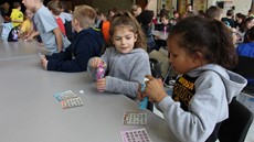 Two young girls at a lunch table in a school auditorium