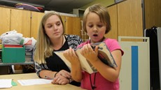 Teacher watching a 5-year-old girl reading