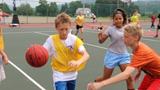 Three children playing basketball on an outdoor court