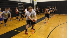 Player holding football with other players in the background in gym