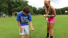 Two children in a field looking at the ground