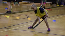 Girl playing field hockey in a gymnasium