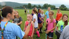 Coach talking to young field hockey players on outdoor field