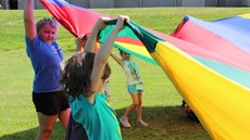 Girls holding up multi-colored tarp