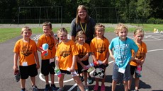 Seven children posing for a picture in front of a teacher outside on a playground