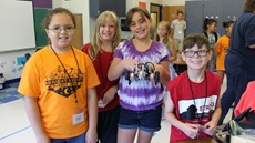 Four children smiling while holding their robot