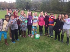 12 elementary school students holding up their arms to show bracelets