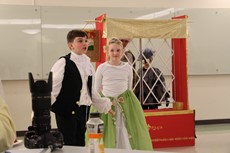 Two students in costume performing on set