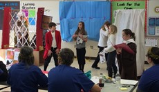 Children in costume performing at the front of a classroom