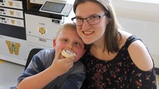 A young boy with a cookie in his mouth and a teenage girl smiling