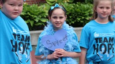 A young girl holds up a heart-shaped sign with the word sweet on it