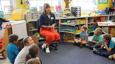 Liz Heller sitting with a group of first grade students sitting around her