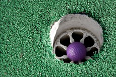 Purple golf ball in a hole