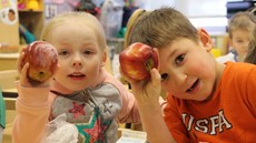 Two young children holding apples