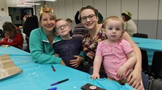 Two women, each holding a young child, all smiling