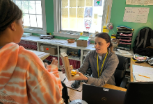 A woman sitting at a desk holding a candy dispenser