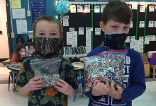 Two young boys in masks holding bags of can tabs