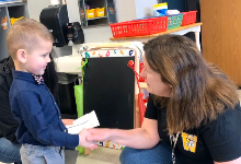 A woman kneeling down in front of a young boy