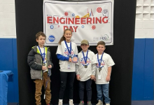 Four children in front of engineering day banner