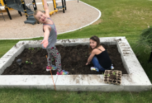 Two smiling young girls in a garden