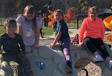 Four young children sitting on a playground structure