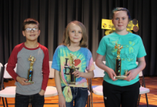 A boy and two girls each holding a trophy