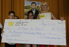 Two children and a woman holding a big check