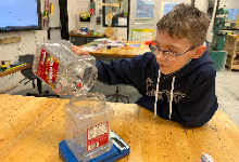 A boy pouring a jar of pop tabs into another jar