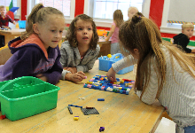 Three young girls at a table working with Lego