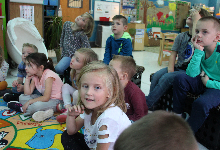 A group of young children sitting on a rug in a classroom