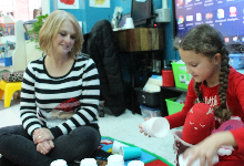 Sherri Abdullah sitting on the floor next to a young girl