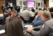 people seated at tables watching two men in the front of a room