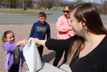 A woman holding a plastic bag in front of a small girl