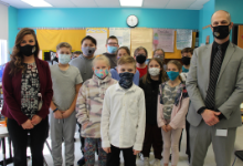 A group of children standing between a man and woman