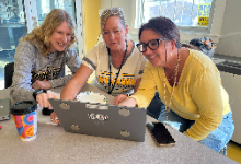 Three women looking at a laptop