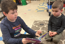 One young boy reading to another