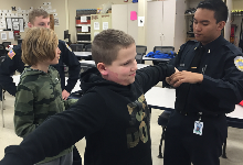 A boy with his arms outstretched with another boy behind him and two men looking on