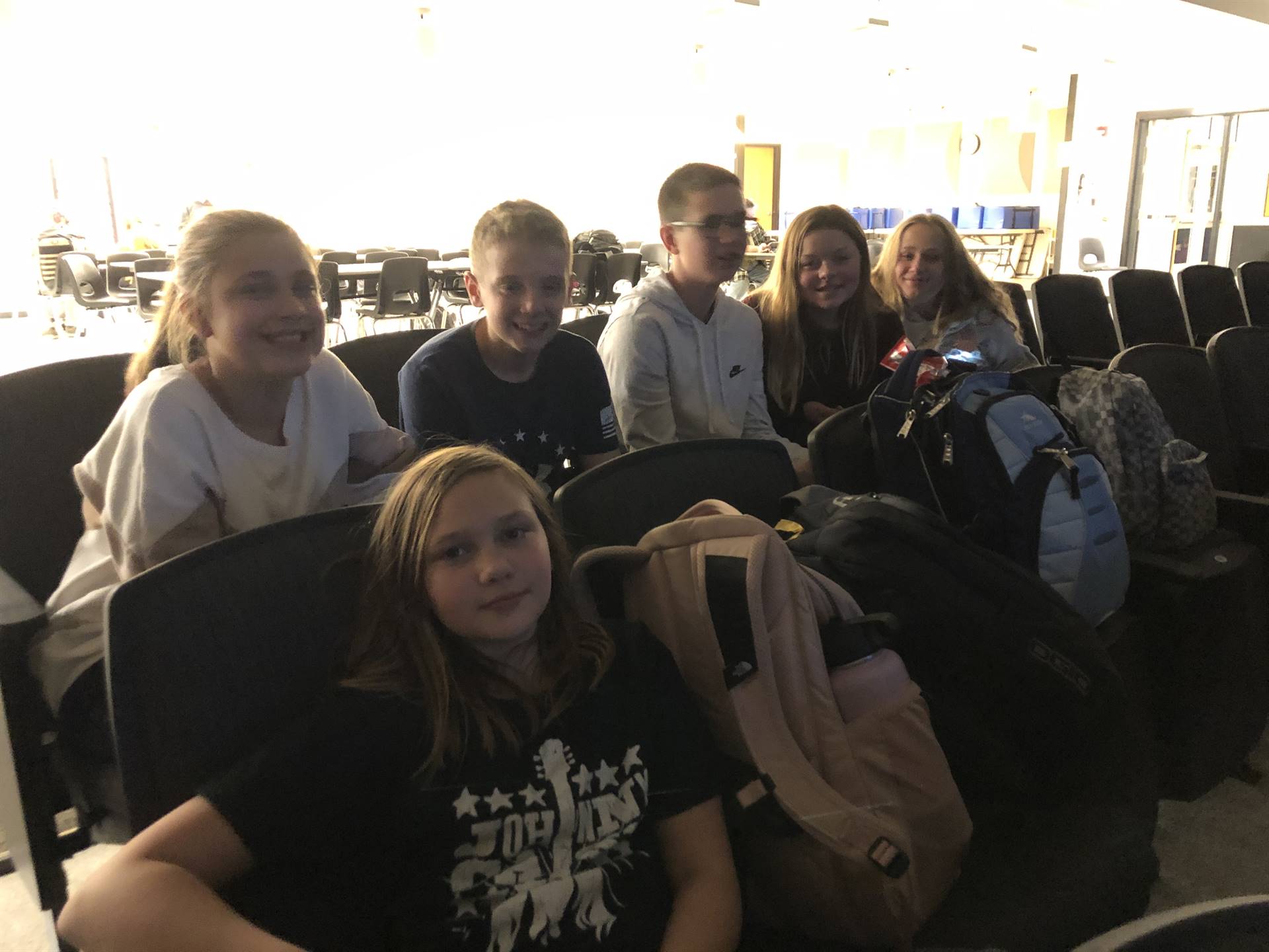 A group of middle school students sitting in auditorium seats
