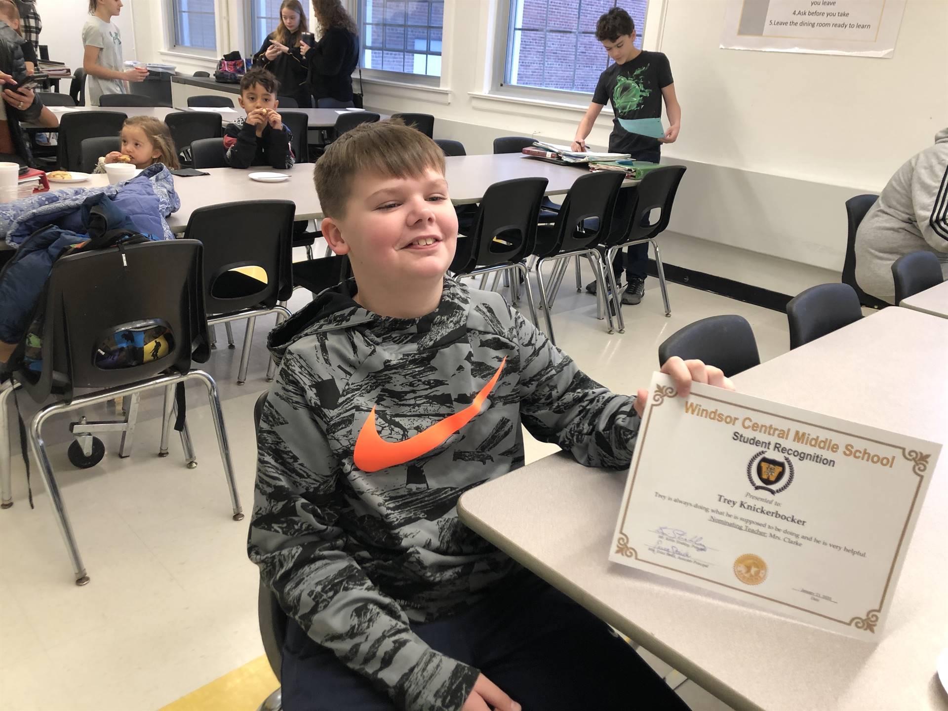 A boy sitting, holding a certificate