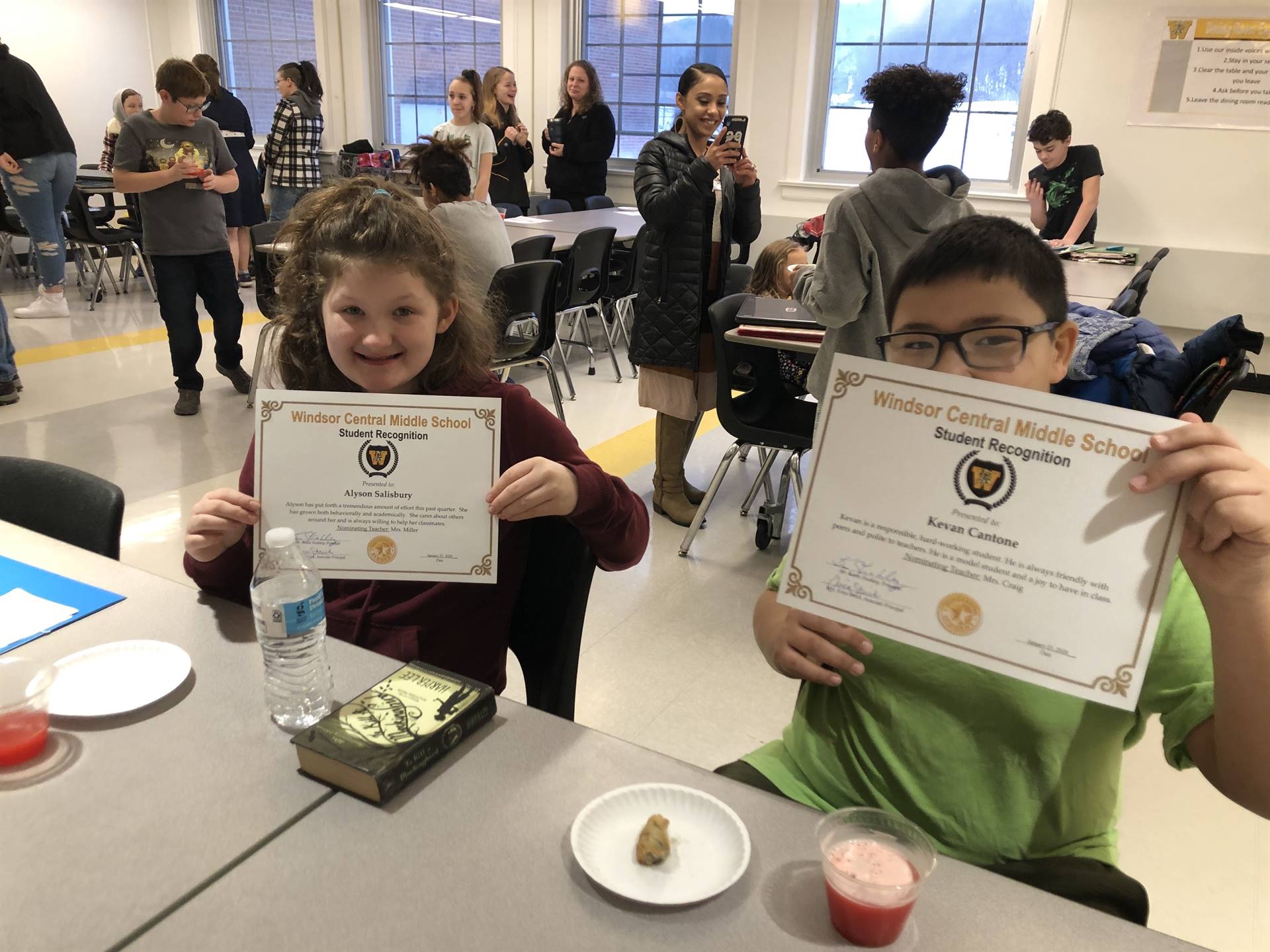 Two children sitting, holding certificates