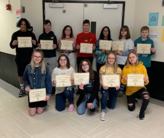 2 Rows of boys and girls holding certificates while standing in a school hallway