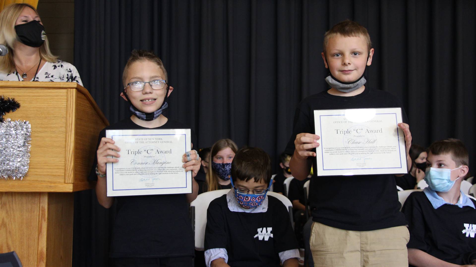 Two young students holding certificates