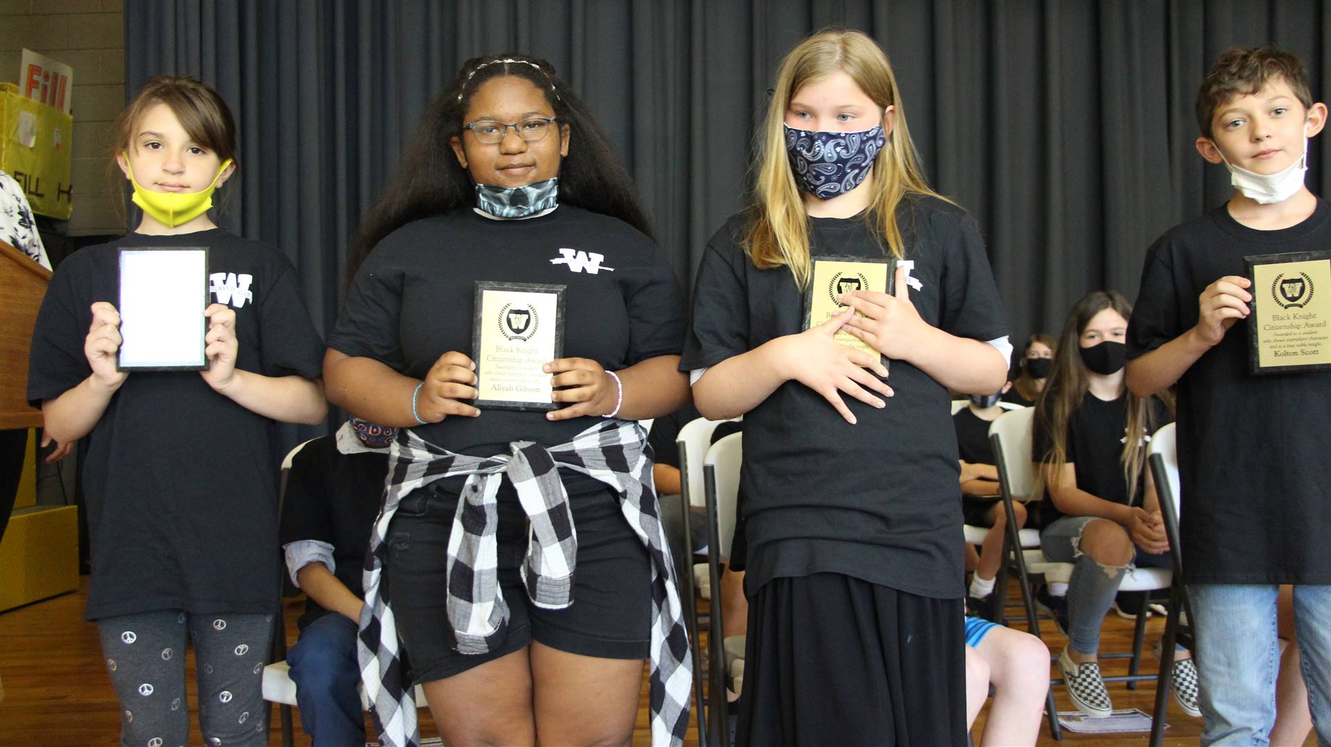 four young students holding plaques