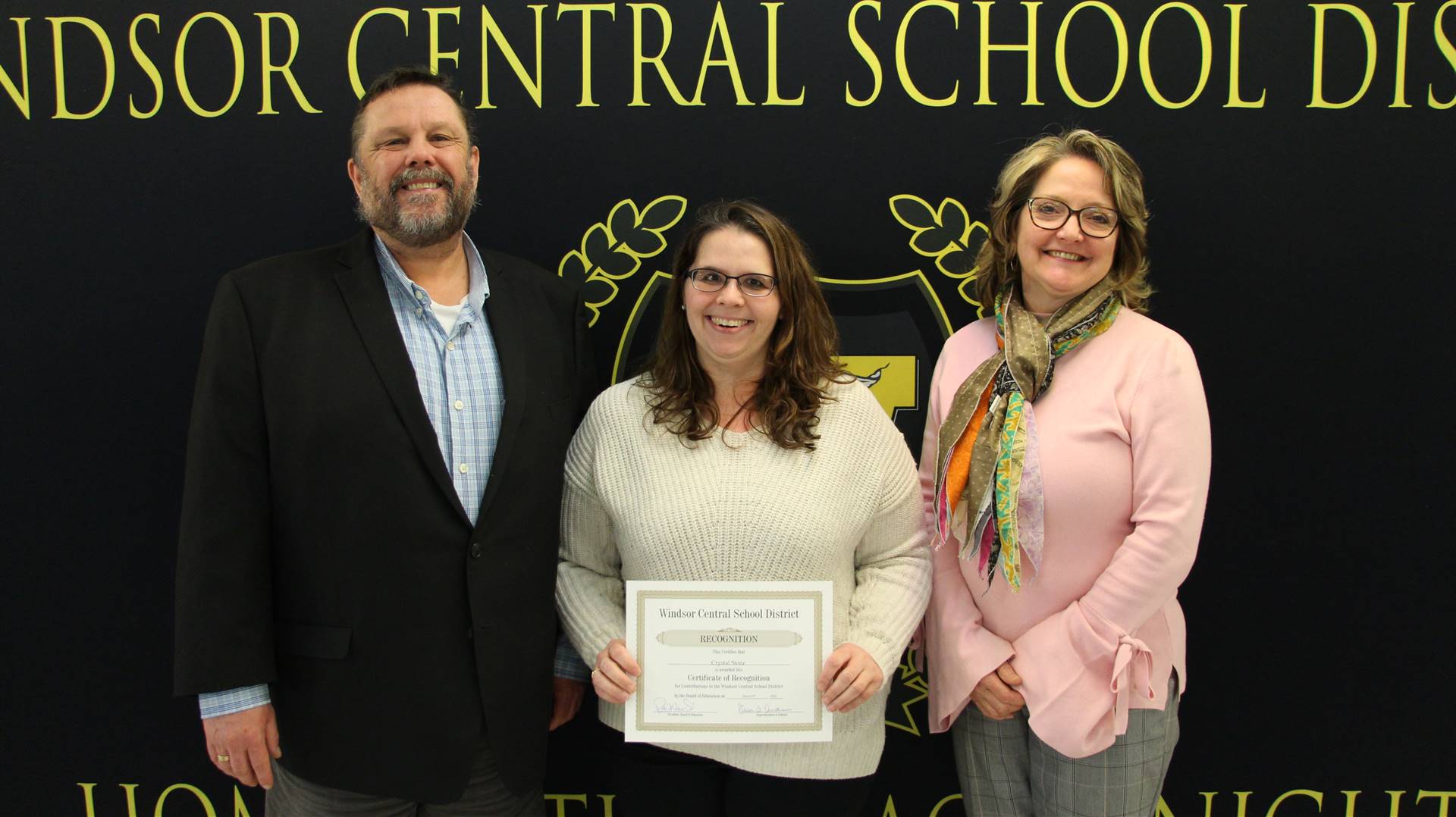 Woman holding a certificate between two other people