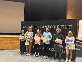 High school students in front of a banner