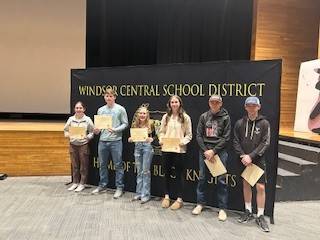 High school students in front of a banner