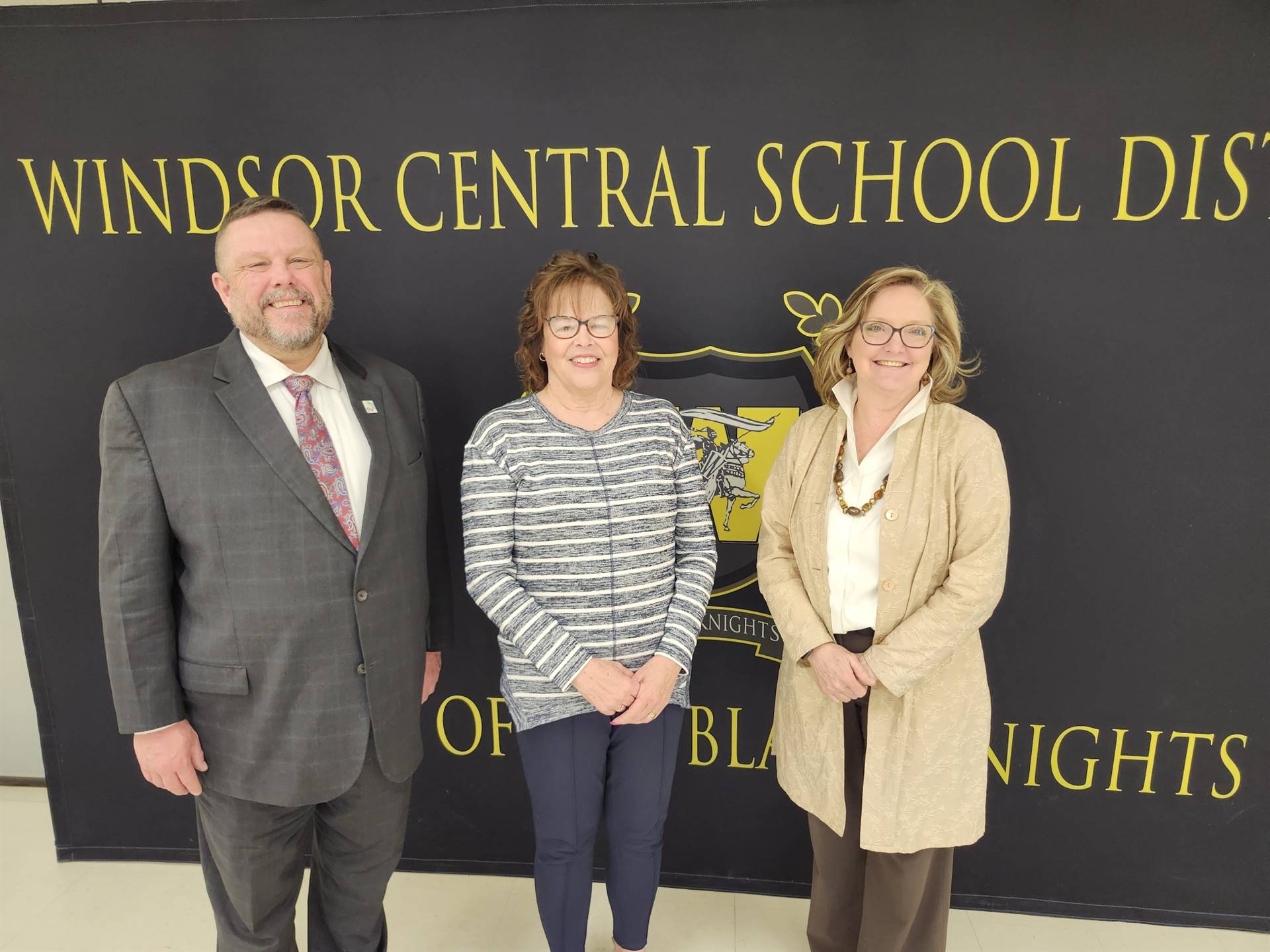 Pete Nowacki, Lynn Klumpp, and Margo Kibbler standing in front of a banner