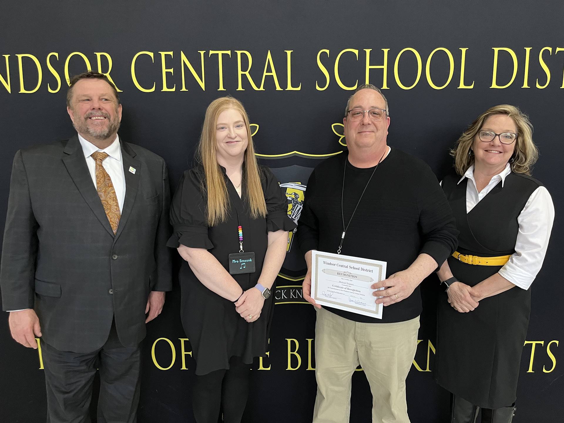 Pete Nowacki, Lindsey Smeenk, Mike Trapani, and Margo Kibbler in front of a banner